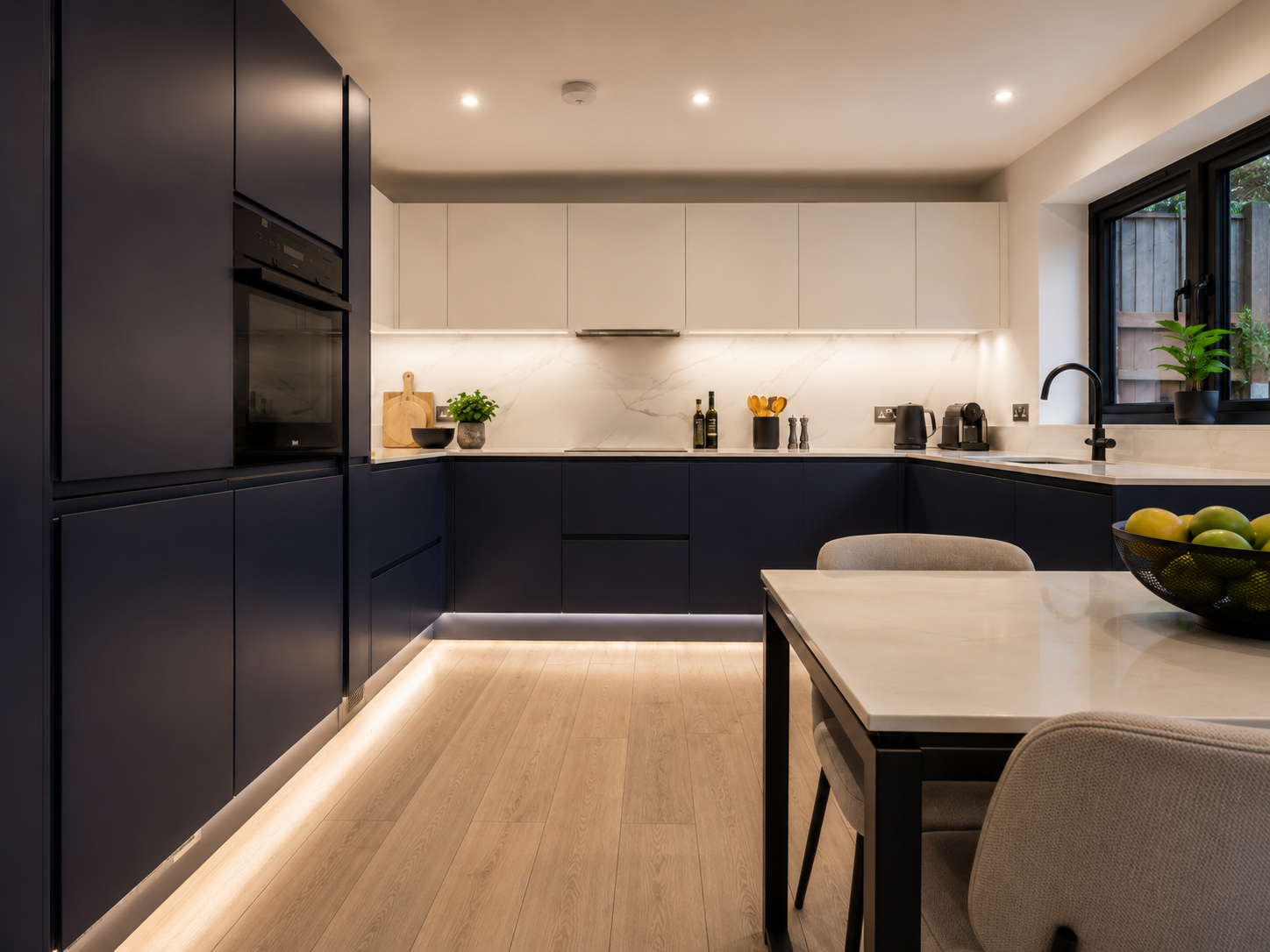 Matte navy handleless kitchen with pale stone worktops