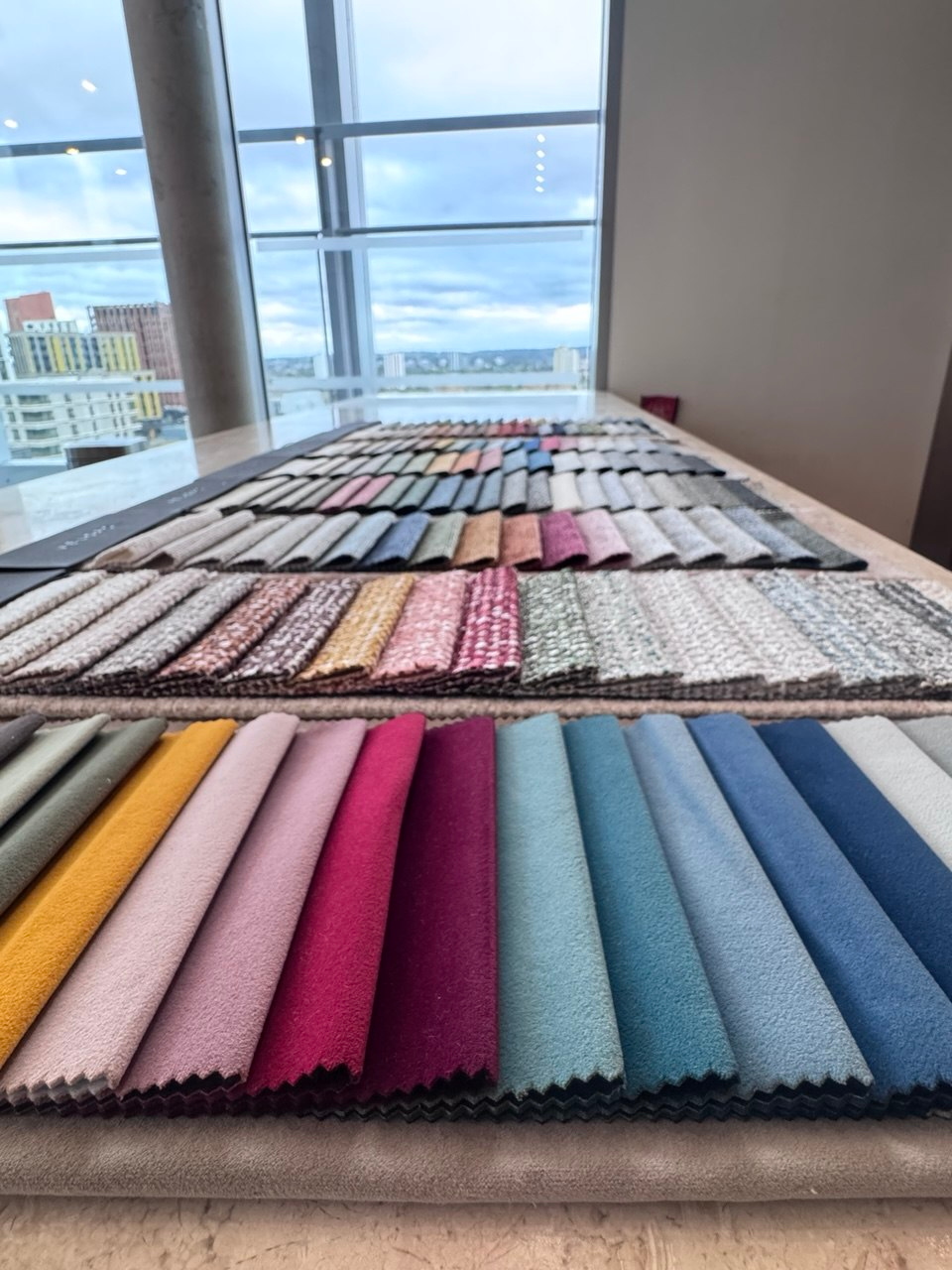 Bespoke sofa fabric swatches laid out on a studio table with a city skyline behind